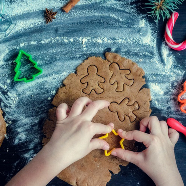 La foto rappresenta un bambino che fa delle formine con l'impasto dei biscotti