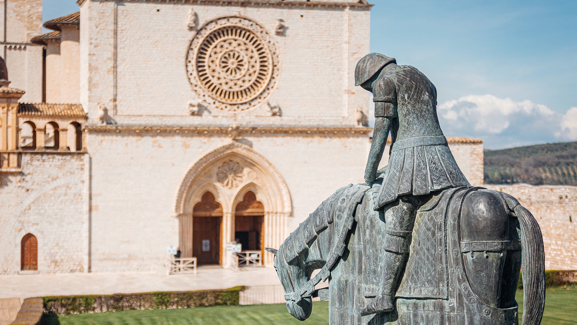 Nell'immagine è presente la scultura in rame dell'uomo a cavallo di fronte alla Basilica Papale di San Francesco