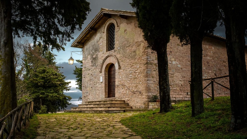 Viale lastricato di pietre, costeggiato da pini, che porta alla Chiesa del borgo di Armenzano.