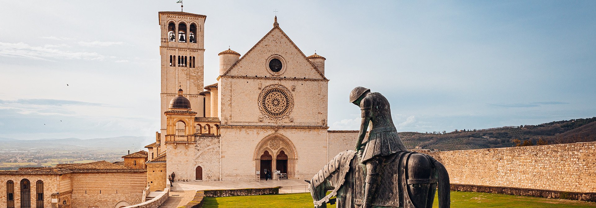 Nella foto possiamo vedere un dettaglio della Basilica Papale di San Francesco, in primo piano è presente la caratteristica statua in bronzo presente davanti all'ingresso della Basilica