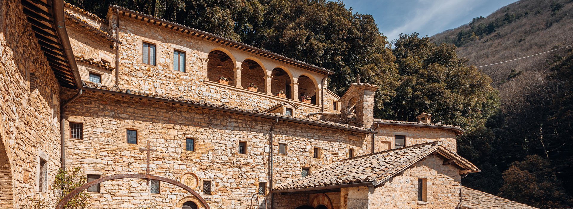 Vista laterale dell'Eremo delle Carceri che ritrae nel dettaglio i semiarchi che danno su una delle terrazze dell'Eremo stesso. Eremo tutto completamente in pietra.
