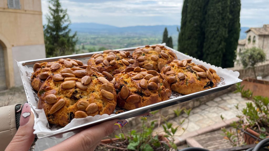 La foto rappresenta una tipologia particolare di pane che si trova ad Assisi, il pane di San Francesco. Uno sfoglia rotonda grande come delle crostatine ma che al suo interno ha tutta verdura ed all'esteno, invece, ha delle mandorle come guarnizione.