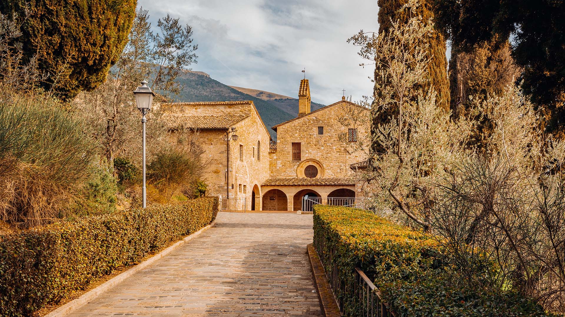Vista dal viale di accesso del Santuario di San Damiano, si intravedono i semiarchi che danno accesso al portico dove è presente anche la porta d'ingresso al Santuario stesso.